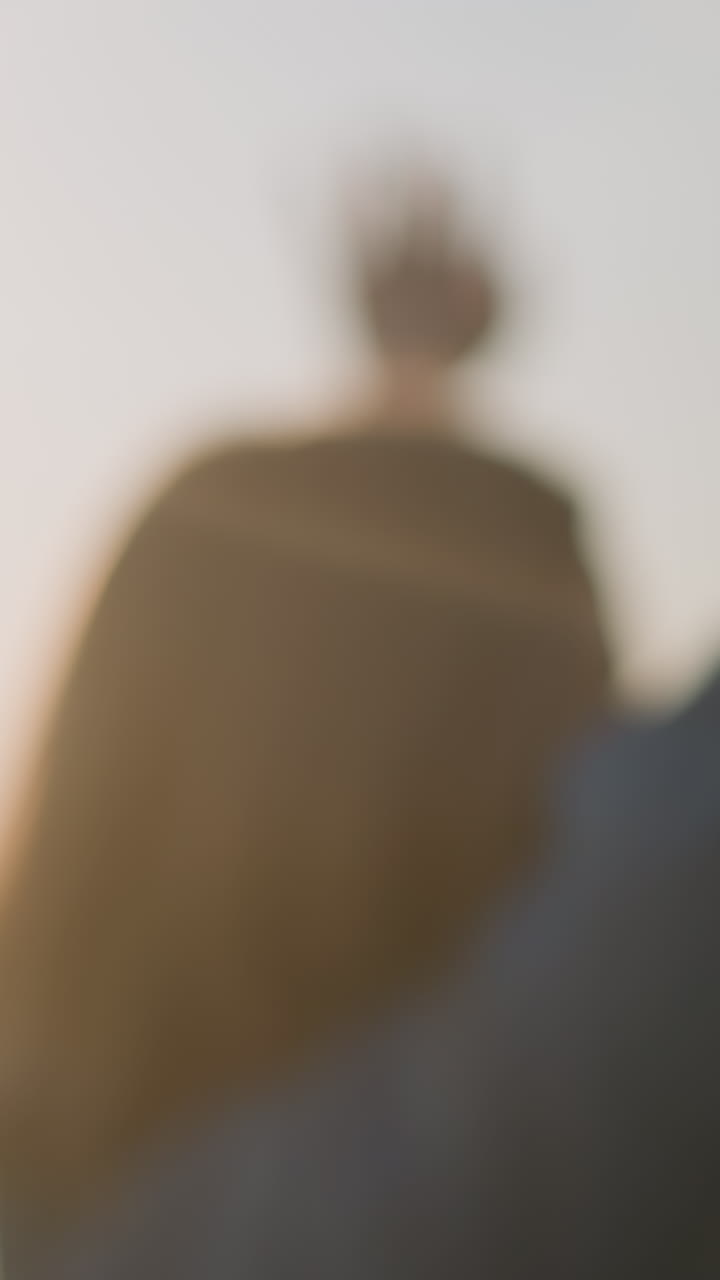 una mujer girando bajo el sol brillante, su figura ligeramente borrosa mientras alegremente se extiende en el aire, rodeada de burbujas flotantes que brillan en la cálida y dorada luz de la puesta de sol