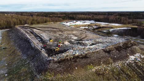 Aerial-flyover-landfill-full-of-trash,-pollution-environmental-problem,-garbage,-trucks-dump-waste-products-polluting-in-a-dump,-wide-angle-drone-shot-moving-forward