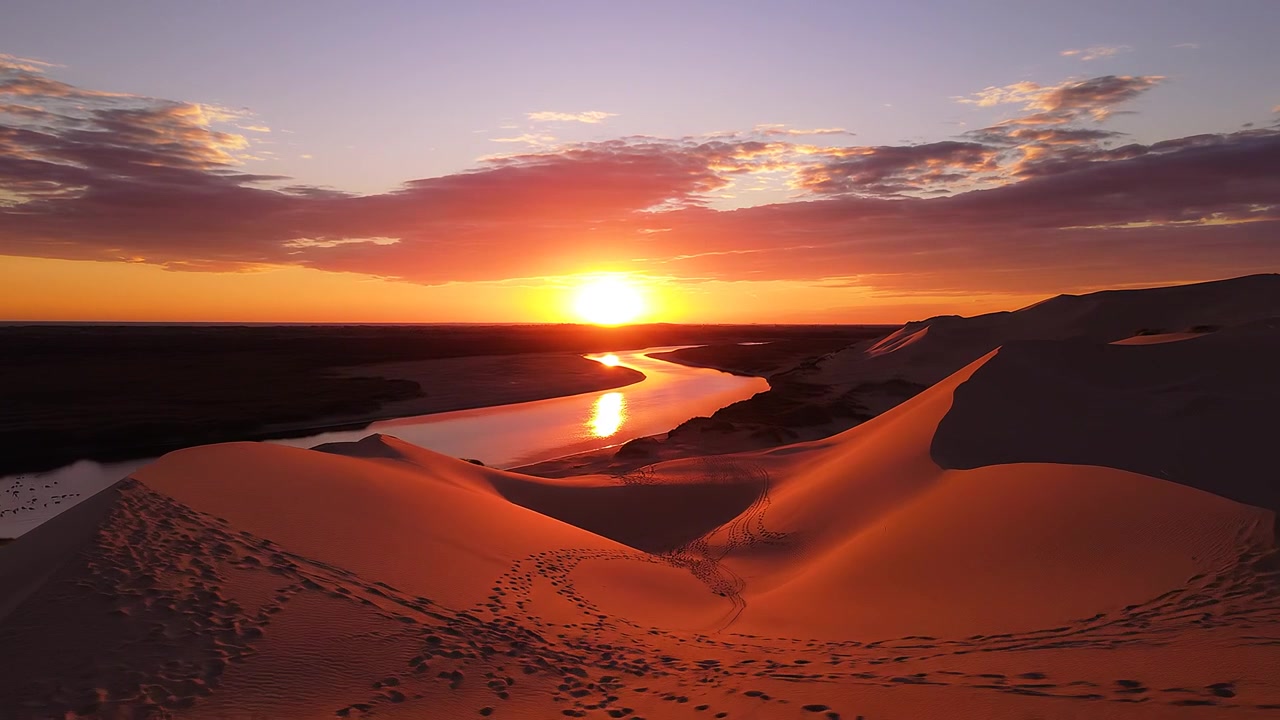 Tramonto vibrante su dune di sabbia del deserto e fiume serpeggiante