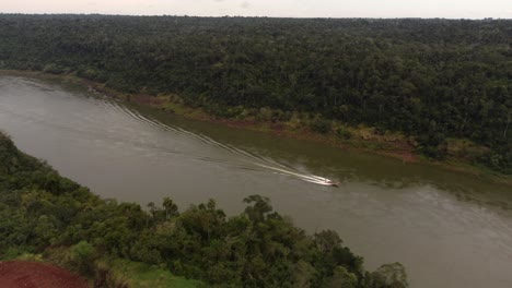 isolated tourist boat sailing along iguazu river at border between argentina and brazil