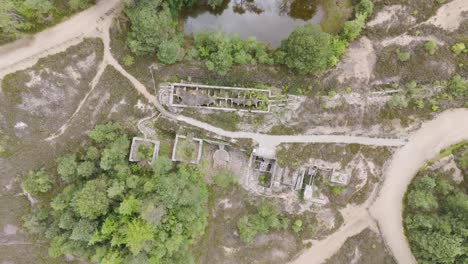 vuelo aéreo de arriba hacia abajo con vistas a los restos de una forja de metal de la revolución industrial, rodeado de vegetación, cornwall, reino unido
