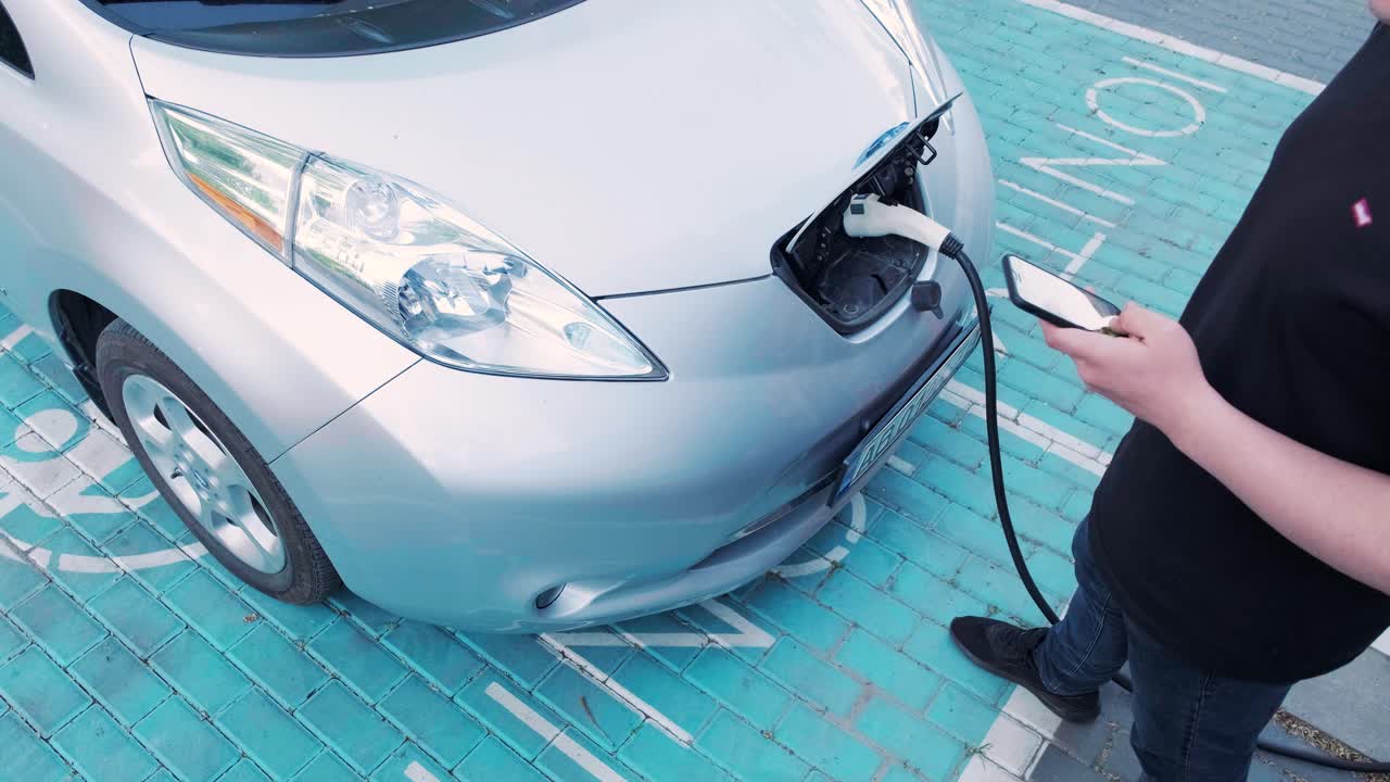 電気自動車の充電プロセス - 電気自動車が充電するハッチの下のショット - 電気車の充電ハッチは自動的に開きます - 男性の手が勃起した車を入します