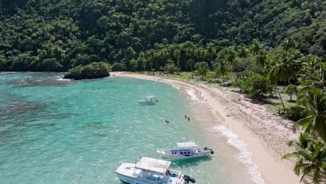 Tropical-sand-beach-with-tourists-and-boats,-turquoise-water,-aerial-forward