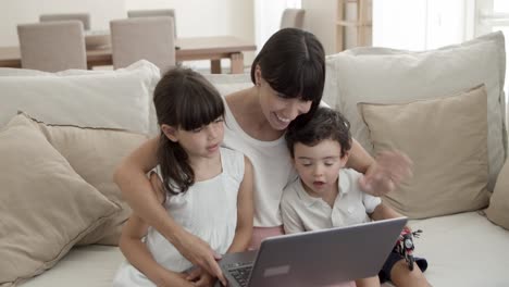 joyful mom and two cute kids using laptop together