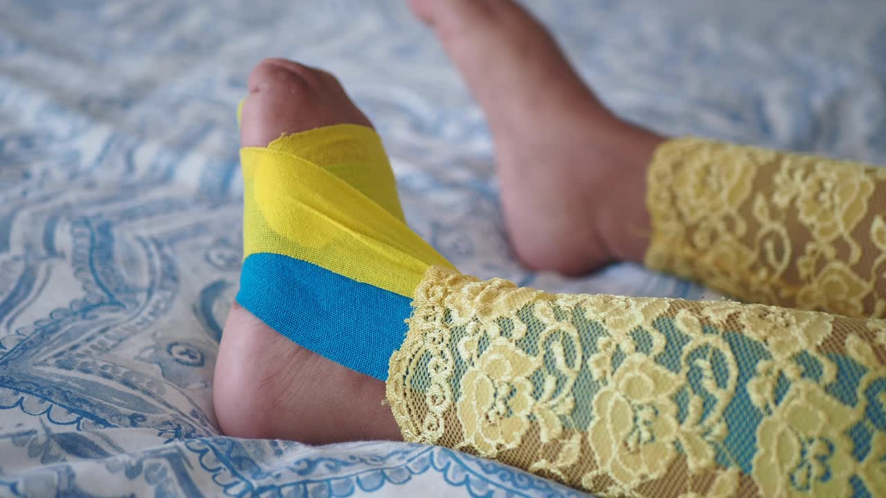 un primer plano del pie de una persona con cinta amarilla y azul envuelta alrededor del tobillo.