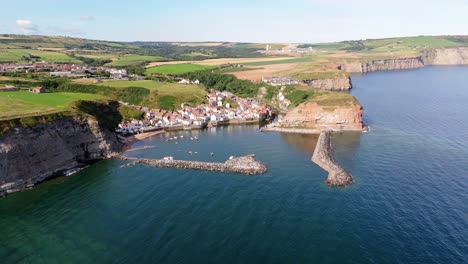 Aerial-drone-view-of-Staithes-Harbour-on-the-North-Yorkshire-coast-with-river,houses,-boats-on-a-sunny-morning-in-August,-summertime