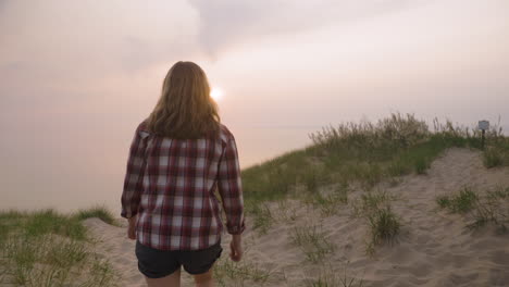 Handheld-shot-of-a-young-woman-watching-the-sunset-over-a-large-body-of-water