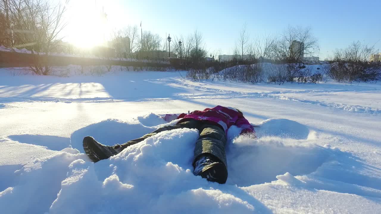 niña haciendo ángel de nieve. vacaciones de invierno