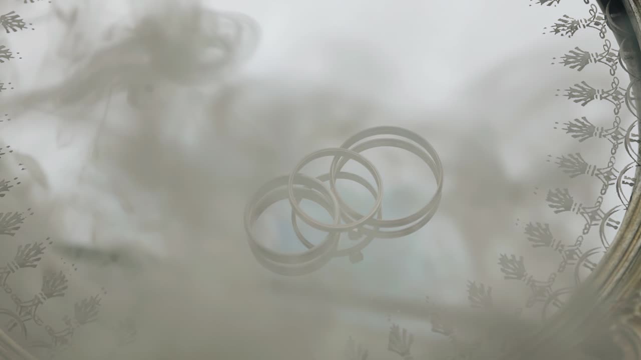 Smoke appears above the rings lying on a mirrored tray. He closes the rings with himself