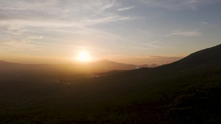 Tomas de dron moviéndose hacia atrás durante el atardecer sobre los paisajes boscosos que rodean el monte Banahaw en Filipinas