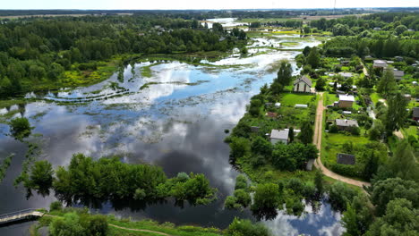 drone view of reflection of sky on lake with aquatic vegetation beside a rural town. natural landscape.