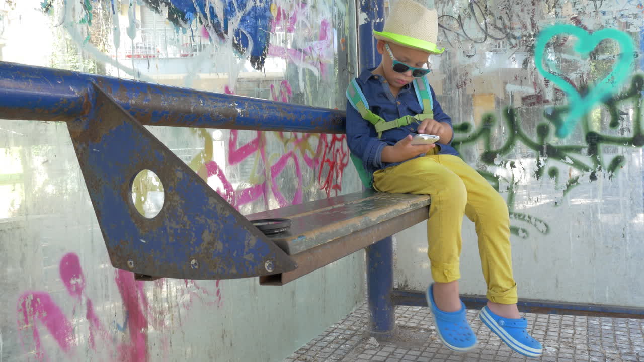 은 버스 정류장에서 스마트폰을 사용하는 아이