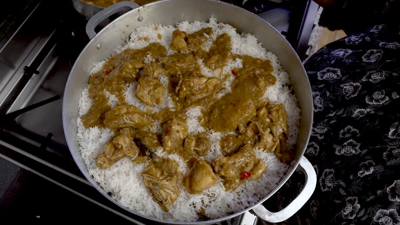 pollo al curry colocado sobre arroz blanco en una olla grande