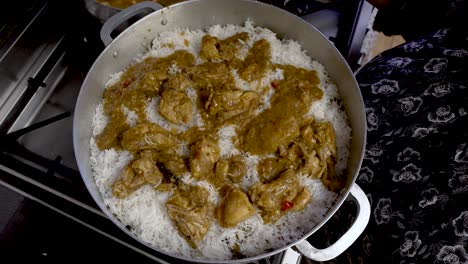 Curry-Chicken-Being-Placed-On-Top-Of-White-Rice-In-Large-Pot