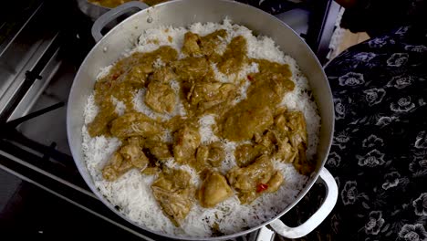 curry chicken being placed on top of white rice in large pot