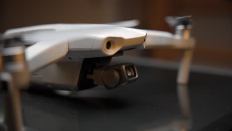 video cinematográfico de primer plano de un dron iluminado con una luz suave desde arriba y luces naranjas en el fondo, filmado en 4k con movimiento de cámara