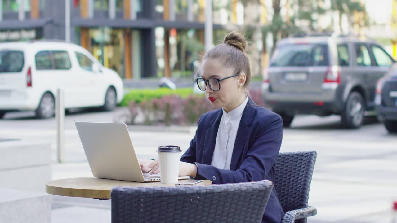 Donna d'affari con laptop in un caffè all'aperto.