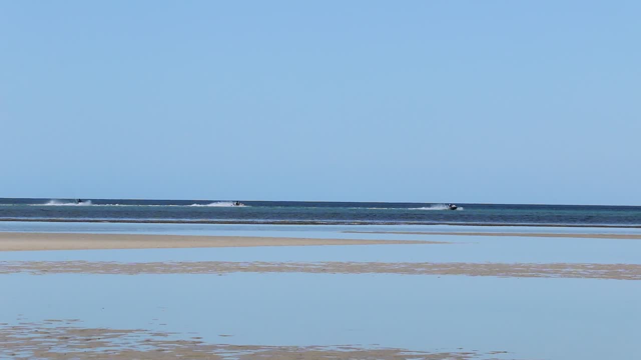 Handheld clip of three jetskis moving across ocean, Australia