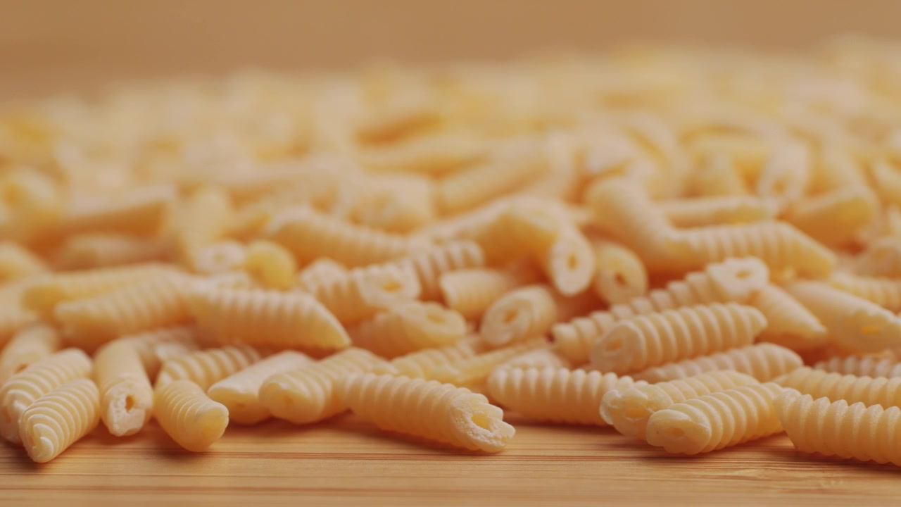 Primo Piano di Pasta Cavatappi Secca e Cruda su una Superficie di Legno