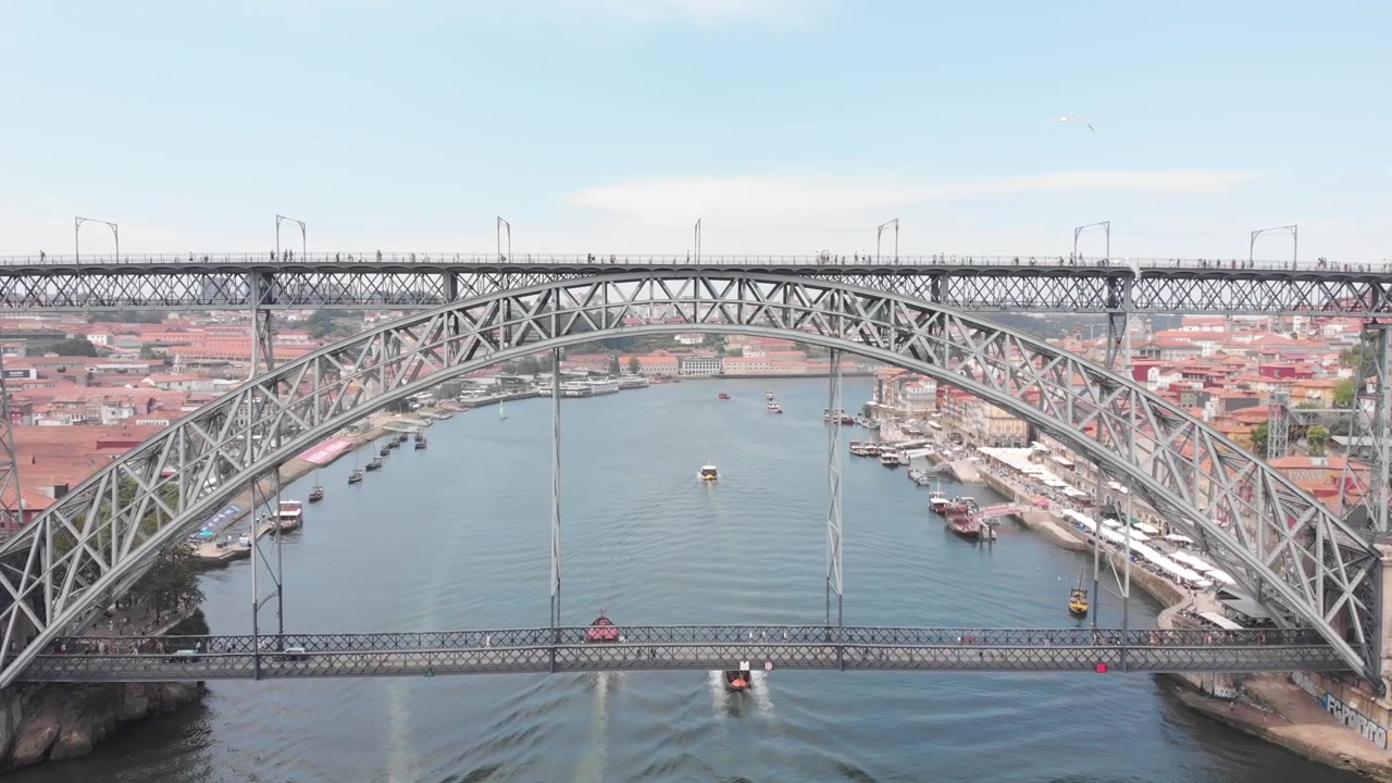 Aerial: Slow drone approach to Dom Luis I Bridge with boats and seagulls on the Douro River, Porto, Portugal