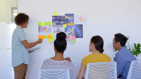 Young-mixed-race-male-executive-explaining-about-graphs-and-sticky-notes-in-modern-office-4k