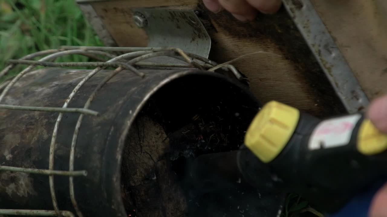 Close-up shot of lighting fire in smoke tool for bees fumigation. Honey bees houses. Natural garden. Apiculture farming.