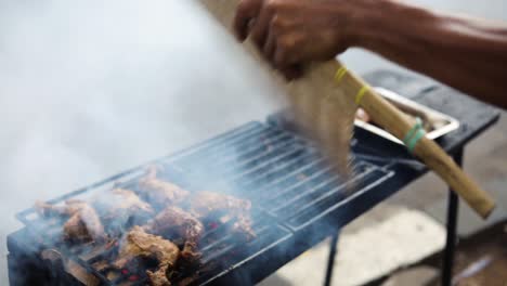 Toma-En-Cámara-Lenta-De-Un-Vendedor-Ambulante-Asiático-Cocinando-Ayam-Bakar-En-Una-Parrilla-Humeante