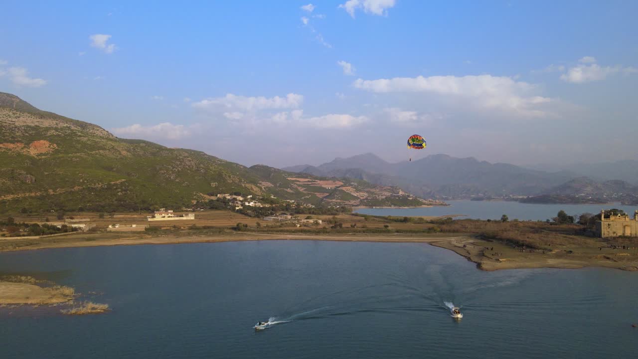 hombre disfrutando de un vuelo en parasailing o de un paseo por encima del lago con un entorno natural