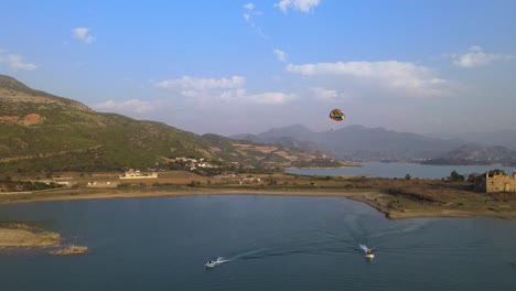 man enjoying parasailing flight or ride above the lake with natural background