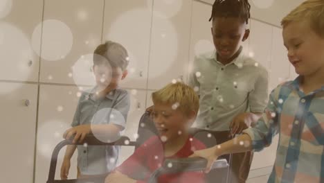 animation of white lights spots over happy diverse schoolboys pushing friend in wheelchair