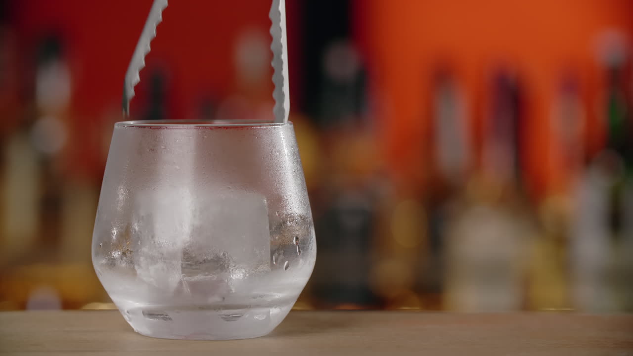 el camarero vertiendo hielo en un vaso.