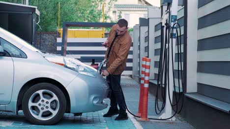 hombre cargando un coche eléctrico en una estación pública