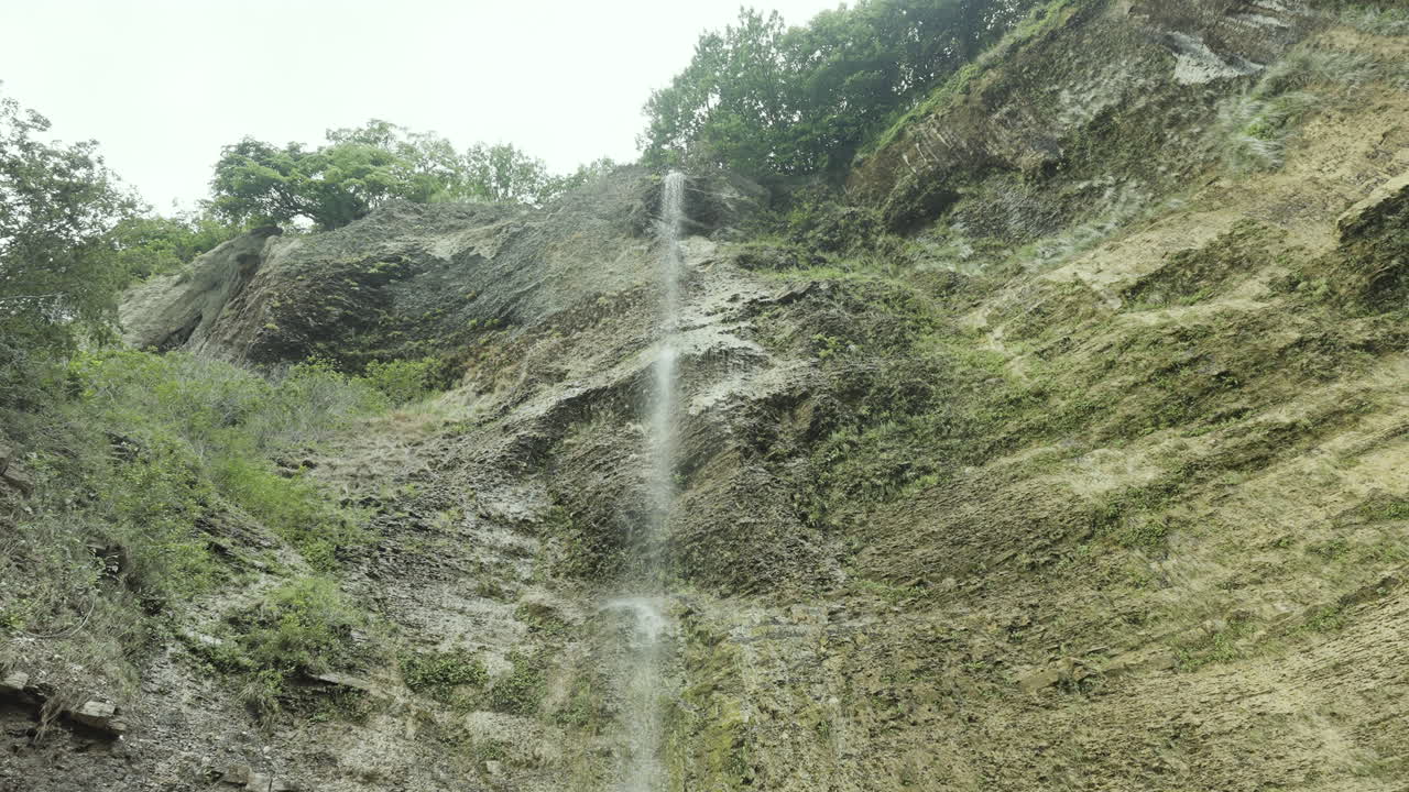 una cascada que cae en cascada por un acantilado rocoso de la montaña
