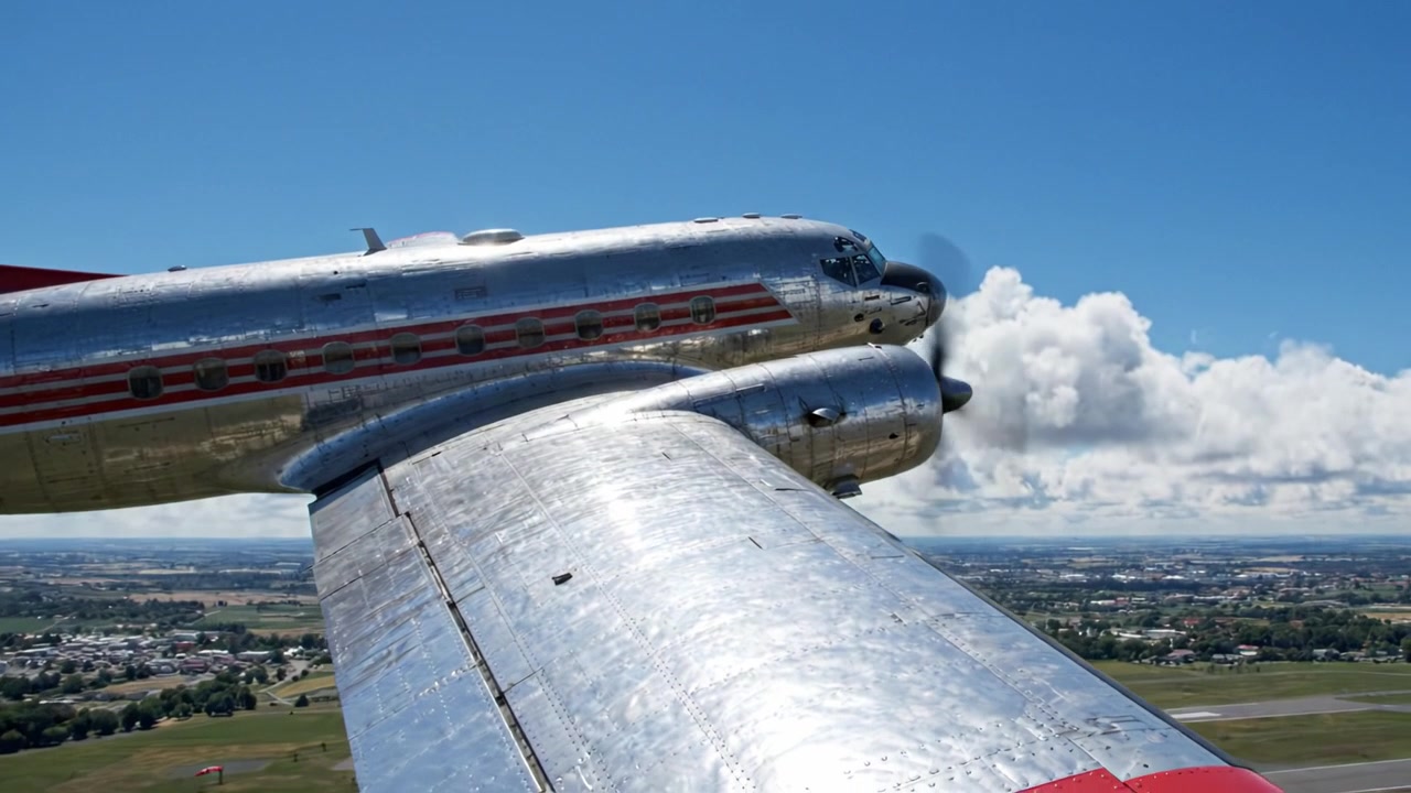 Maravilha da Aviação: Vistas Cativantes de uma Aeronave Vintage Planando pelo Céu com Paisagens Deslumbrantes Abaixo, Mostrando Suas Asas Prateadas Brilhantes e Design.