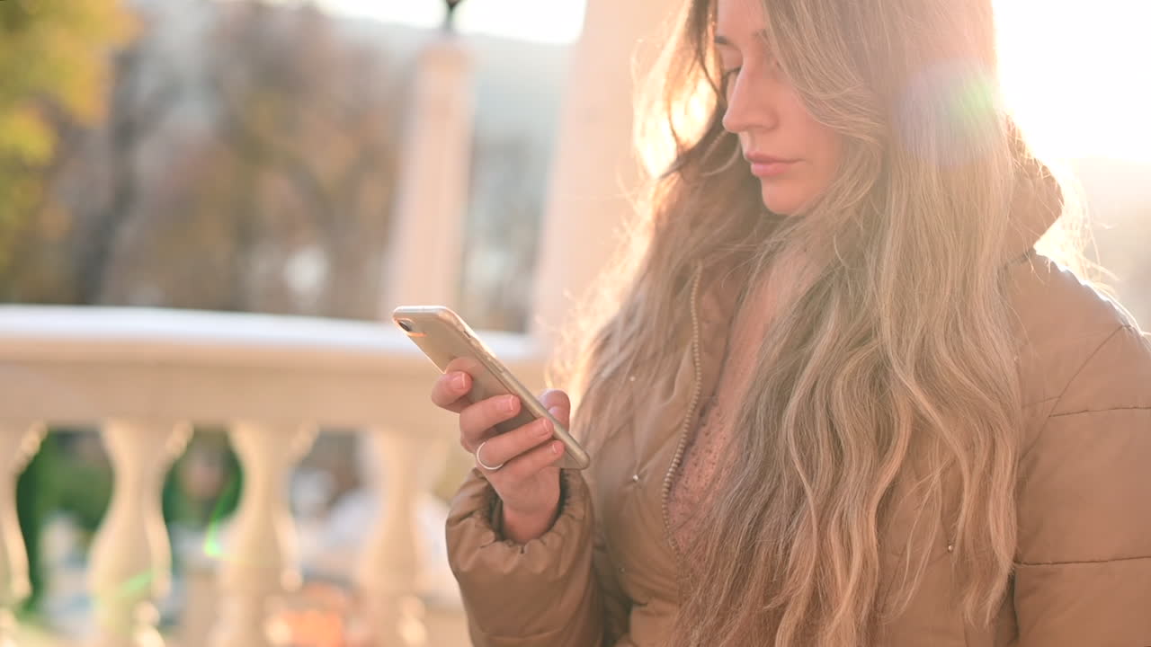 CHISINAU, MOLDÁVIA - 03 DE NOVEMBRO DE 2021: Mulher trabalhando em um iPhone branco em um parque ao pôr do sol