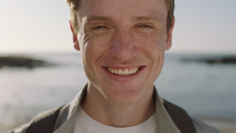 retrato de cerca de un joven de cabeza roja riendo alegremente en una hermosa playa soleada sintiéndose feliz