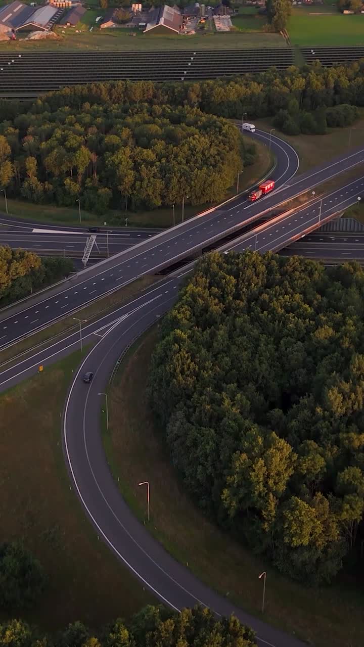 Vista aerea di uno svincolo autostradale con traffico e pannelli solari all'ora d'oro