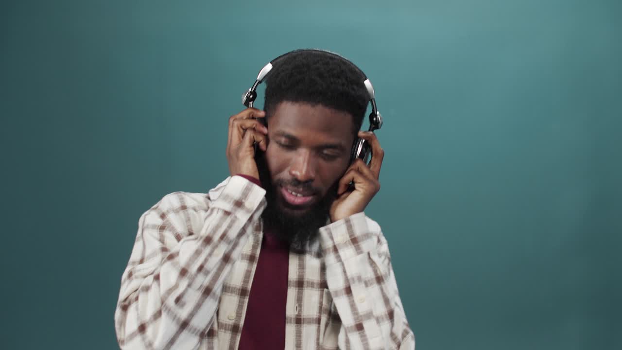 un joven africano con una camisa blanca está escuchando música y bailando