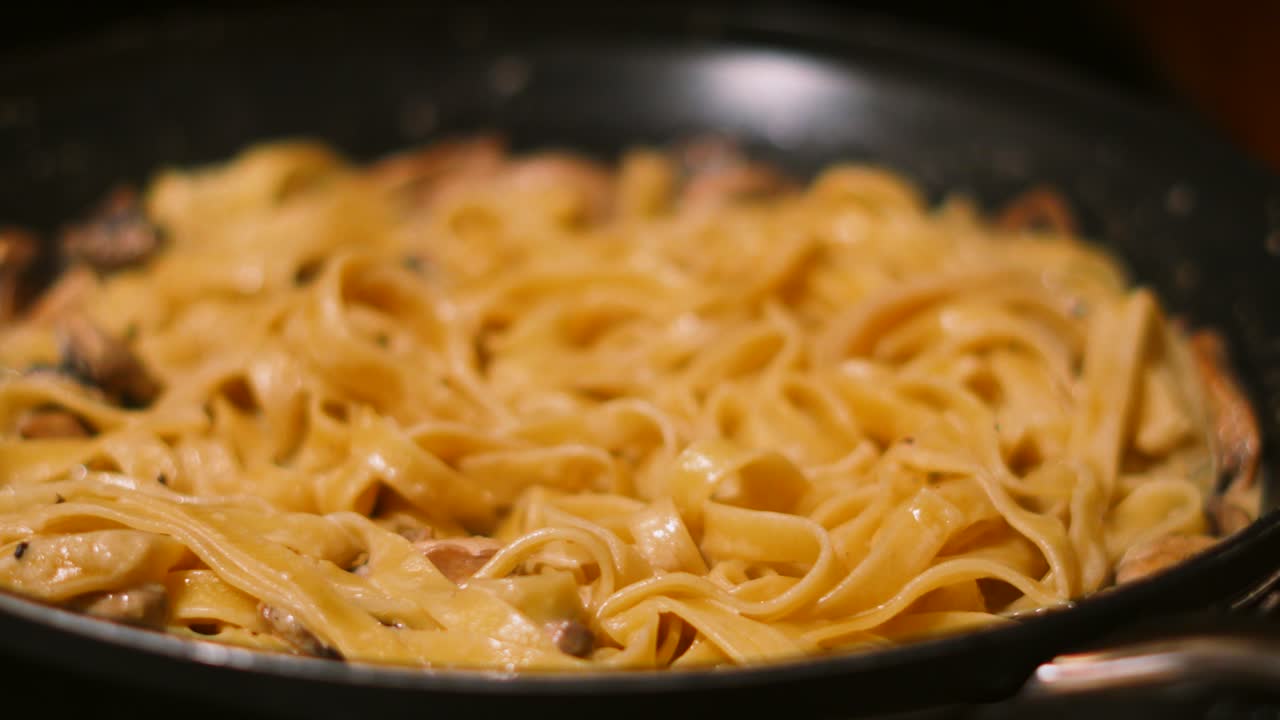deliciosa cremosa cocina italiana comida tagliatelle pasta de setas que se cocina en la sartén en la cocina 4k