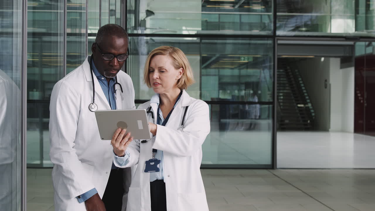 Médico e médica em reunião informal em um hospital moderno olhando para um tablet digital