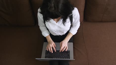 young woman using laptop at home sitting on sofa