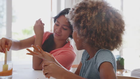 Two-pre-teen-girlfriends-having-fun-with-modelling-clay-and-water-at-home,-close-up,-side-view