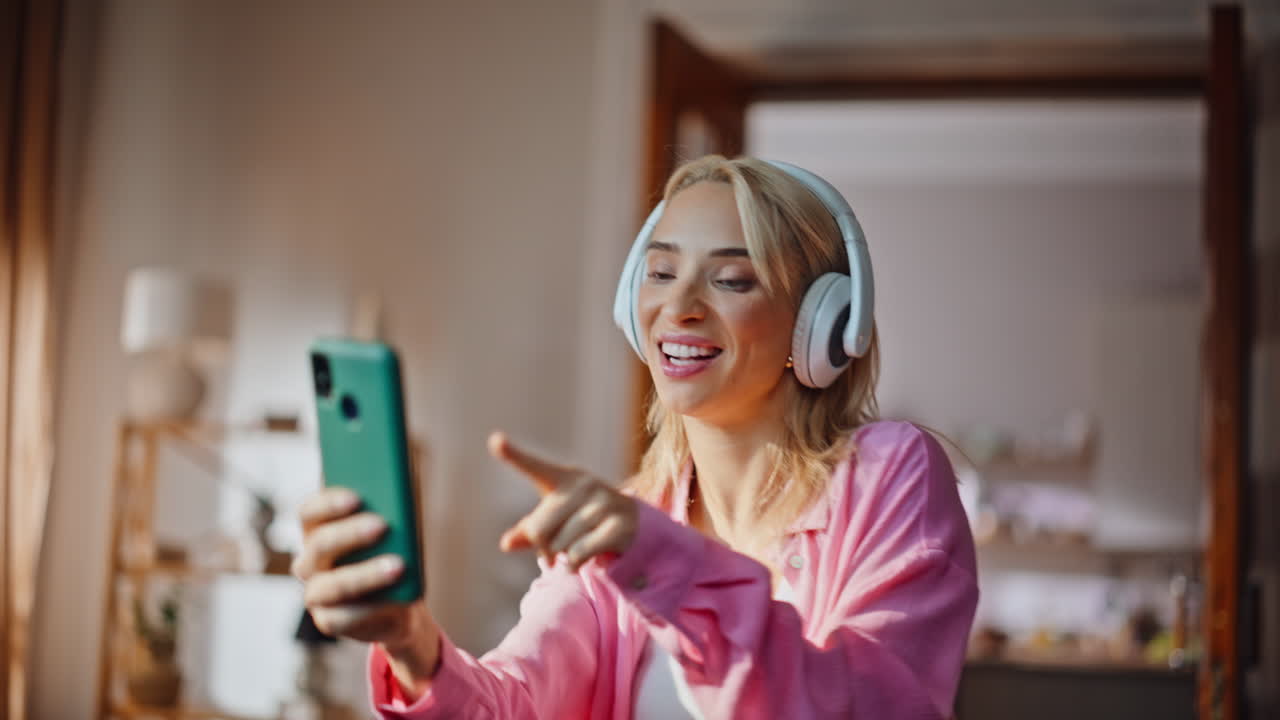 Music lover girl dancing in bright apartment portrait. Woman recording herself