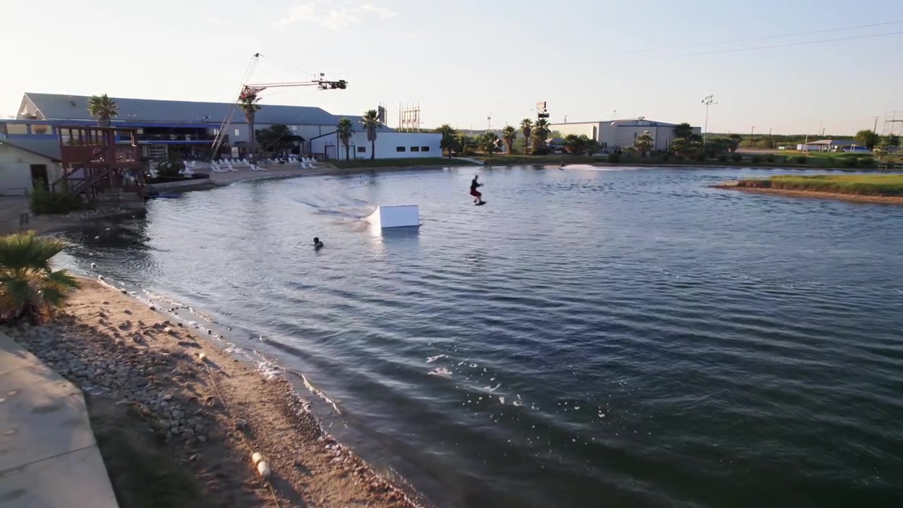 Actionsportare åker wakeboard i en kabelpark under solnedgången på sommaren