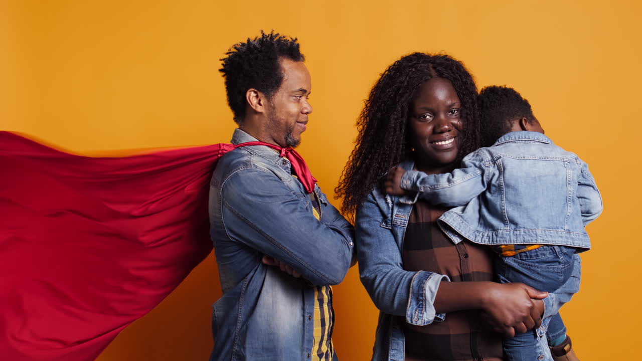joven padre con una capa de superhéroe siendo un salvador y un héroe para su hijo bebé