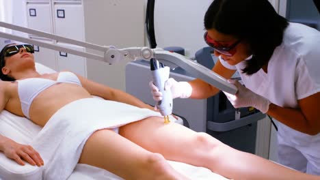 doctor performing laser hair removal on female patient skin