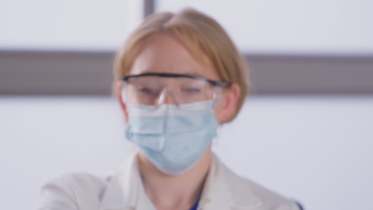 Portrait Of Female Lab Research Worker Wearing PPE Holding Test Tube Labelled Omicron