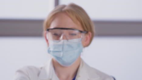 retrato de una investigadora de laboratorio que lleva un ppe con un tubo de ensayo etiquetado como omicron