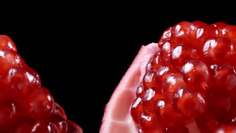 shooting of rotating red pomegranate seeds on black background