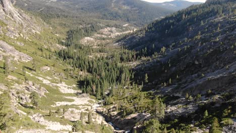 4k ariel drone footage flying over a mountain waterfall in the sierra nevada peaks and trees, rushing water from snow melt flows into the american river in desolation wilderness
